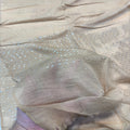 A close-up of a beige sheer fabric with delicate silver sequin embroidery arranged in geometric patterns, draped to show its texture and sheen.
