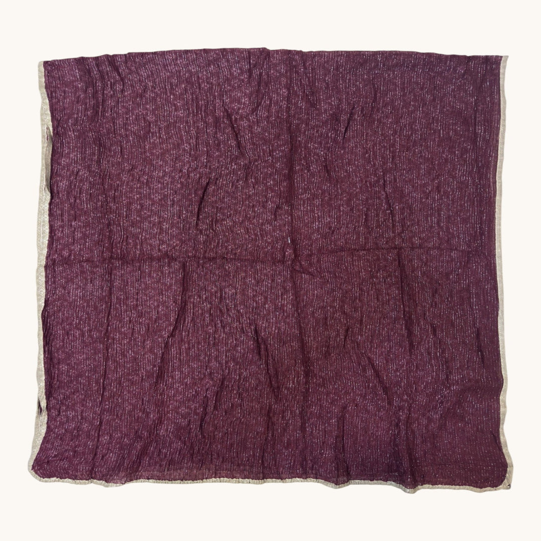A square piece of textured purple fabric with a frayed, raw edge, laid flat against a light off-white background.