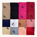 Twelve folded fabric swatches arranged in a 3x4 grid, each showing a different solid color with a small black paisley motif. The colors include beige, black, bright pink, dark red, navy, white, tan, light pink, light blue, peach, and red, on a light cream background.