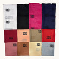Twelve folded fabric swatches arranged in a 3x4 grid on a light beige background. The fabrics include white, black, bright pink, navy, burgundy, peach, taupe, red, dusty rose, brown, cream, and light blue, each with a small black Greek key pattern near the top.