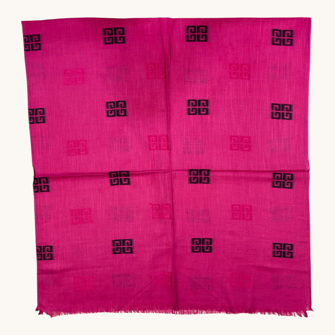 A bright pink woven textile, likely a scarf or sari, featuring a repeating pattern of black Greek key motifs and subtle pink medallions on a light beige background.