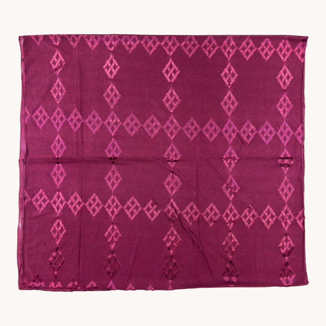 A rectangular magenta purple fabric, likely a silk scarf or sari, featuring a repeating pattern of vertical columns of pink diamond (ikat) motifs, displayed flat against a light cream background.