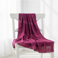 A magenta purple patterned scarf draped over a white wooden chair in a bright, minimalist room.
