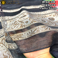 A close-up of a sheer black organza pallu stole with metallic gold and silver floral patterns, held by a hand to show its drape and texture.