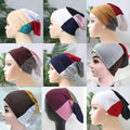 Collection of mannequin heads wearing colorful headscarves with a blurred green background.